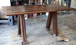 Victoria Table - Walnut table top with custom 4x4 V base with locked casters for a restaurant